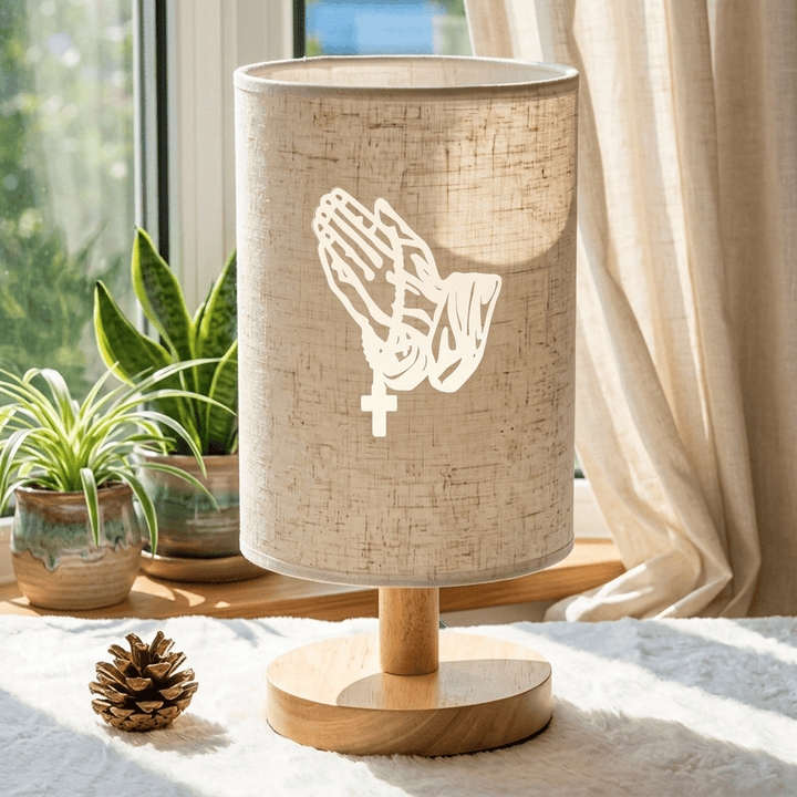 Christianartworkshop Lampada da tavolo con base in legno naturale e paralume in tessuto, motivo mani in preghiera con croce: un'oasi di pace e devozione notturna. - image 3