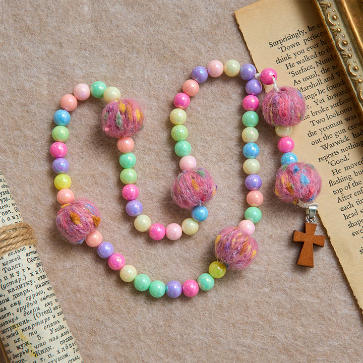 Christianartworkshop Rosario per bambini con perline a forma di macaron e pompon soffici, con croce in legno: emblema di innocente gentilezza celeste. - Rosario soffice color macaron - image 0